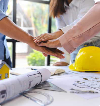 Equipo de arquitectos uniendo manos sobre planos y casco de obra